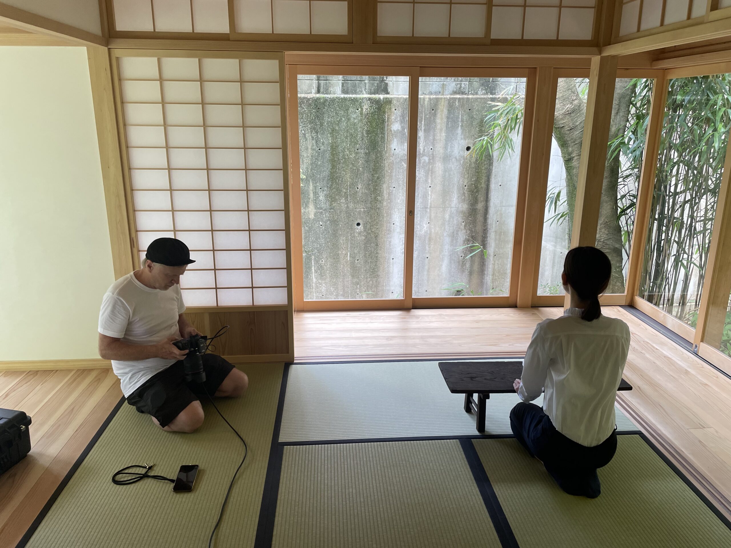 Risa kneeling at a small desk while Martin gets the camera ready